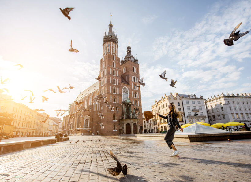 Krakow city in Poland View on the central square and famous st. Marys basilica with pigeons flying during the sunrise in Krakow, Poland