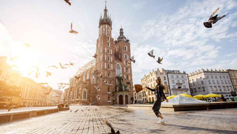 View on the central square and famous st. Marys basilica with pigeons flying during the sunrise in Krakow, Poland